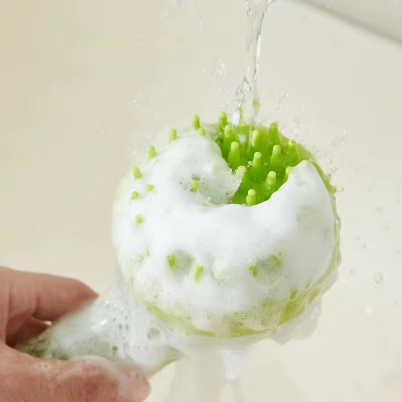 Green CoatKind bath brush covered in shampoo lather